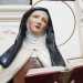 Riconosciamo, incastrata tra banchi rovesciati, la statua lignea di Teresa DAvila, vestita in abiti monacali, con lo sguardo in contemplazione e un testo sacro aperto nella mano sinistra 